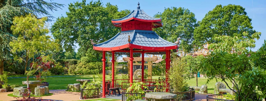 Red pagoda surrounded by trees and landscaped planting in the Japanese Garden at Paultons Park